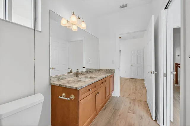 an empty room with wooden floor chandelier fan and windows