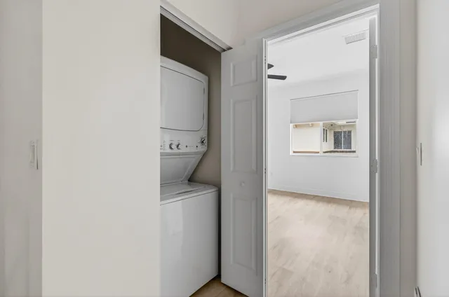 a view of an empty room with window and a kitchen view