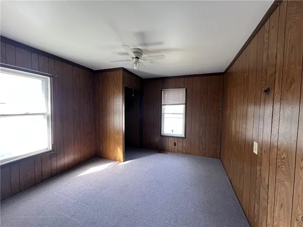 an empty room with windows and chandelier fan