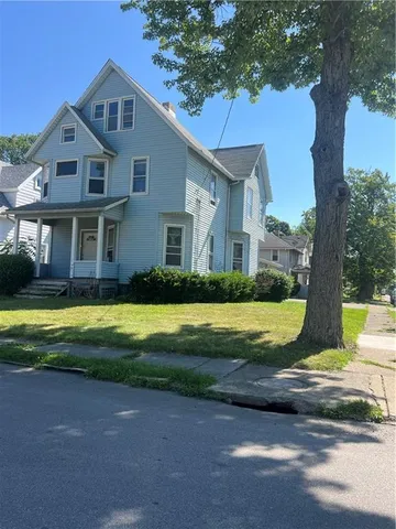 a view of a house with a big yard plants and a large tree