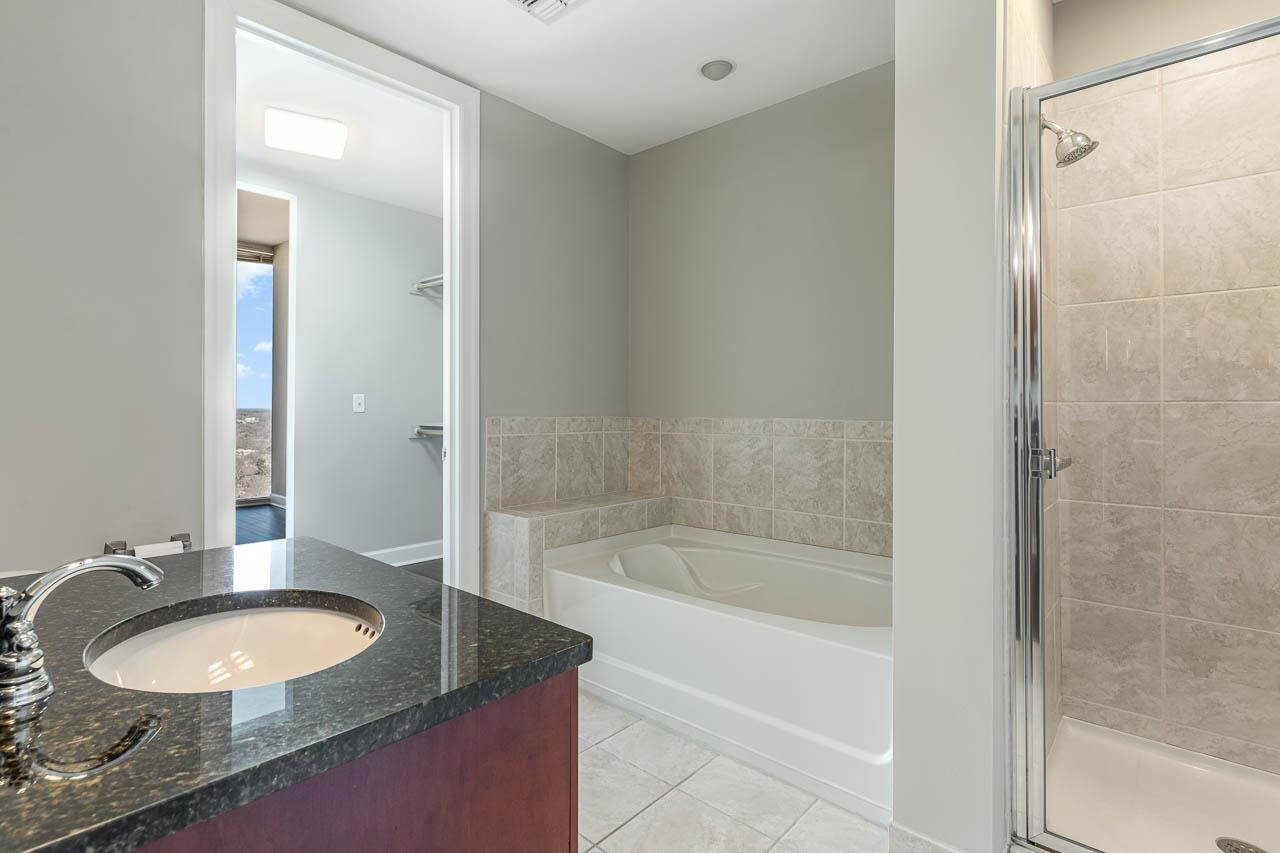 301 Fayetteville Street, Unit 2305 Raleigh, NC 27601 - Photo 7 of 23 a bathroom with a granite countertop sink a mirror and a bathtub