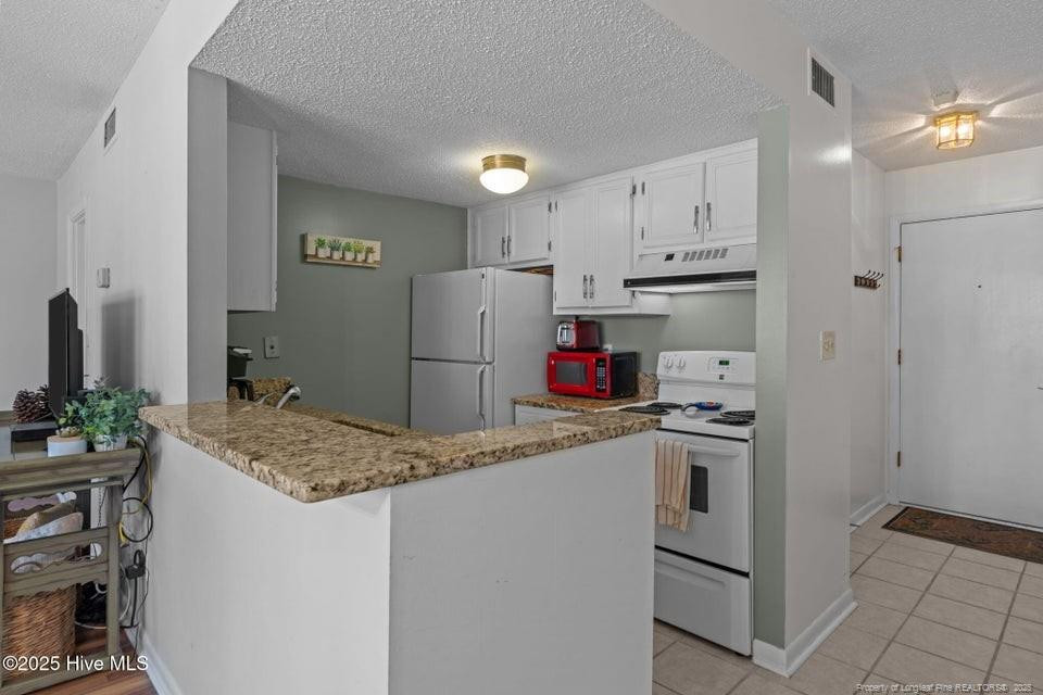 10 Pine Tree Road, Unit 211 Lakeview, NC 28350 - Photo 21 of 36 a kitchen with refrigerator and cabinets