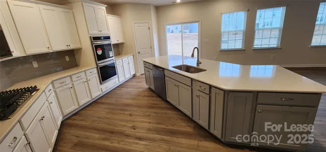 a kitchen with stainless steel appliances granite countertop a stove a sink and a refrigerator