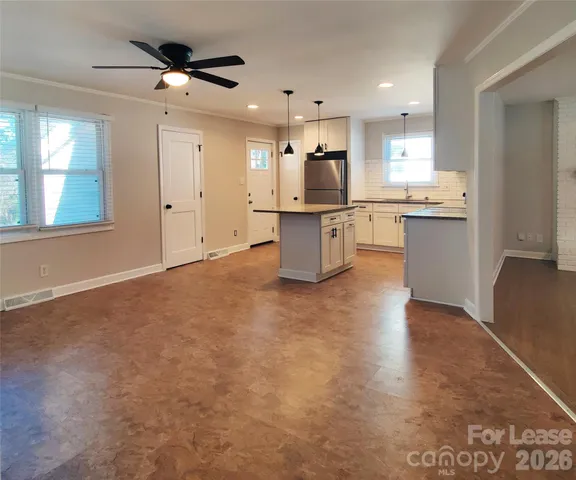 a view of kitchen with stainless steel appliances kitchen island refrigerator stove a sink dishwasher and a fireplace with wooden floor