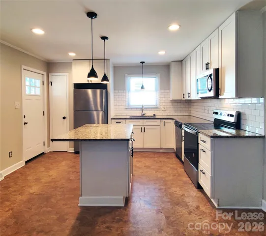 a kitchen with stainless steel appliances granite countertop a sink a stove a refrigerator and island with wooden floor