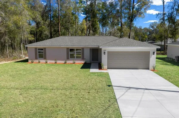 a front view of house with yard and trees in the background