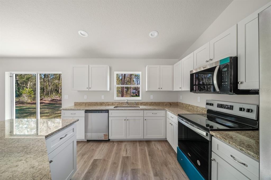 8992 North Lisa Terrace Citrus Springs, FL 34433 - Photo 8 of 25 a large kitchen with a stove top oven a sink a microwave and wooden floor