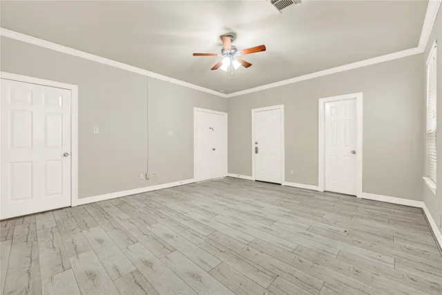 an empty room with wooden floor and ceiling fan