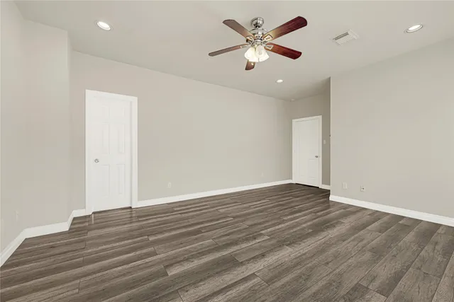an empty room with wooden floor and ceiling fan
