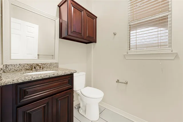 a bathroom with a granite countertop toilet sink and mirror