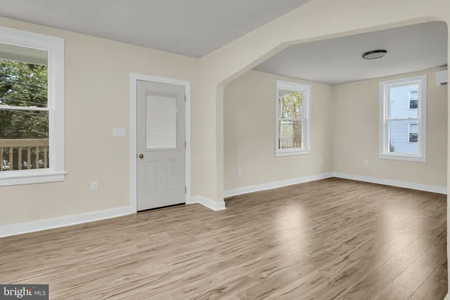 an empty room with wooden floor and windows