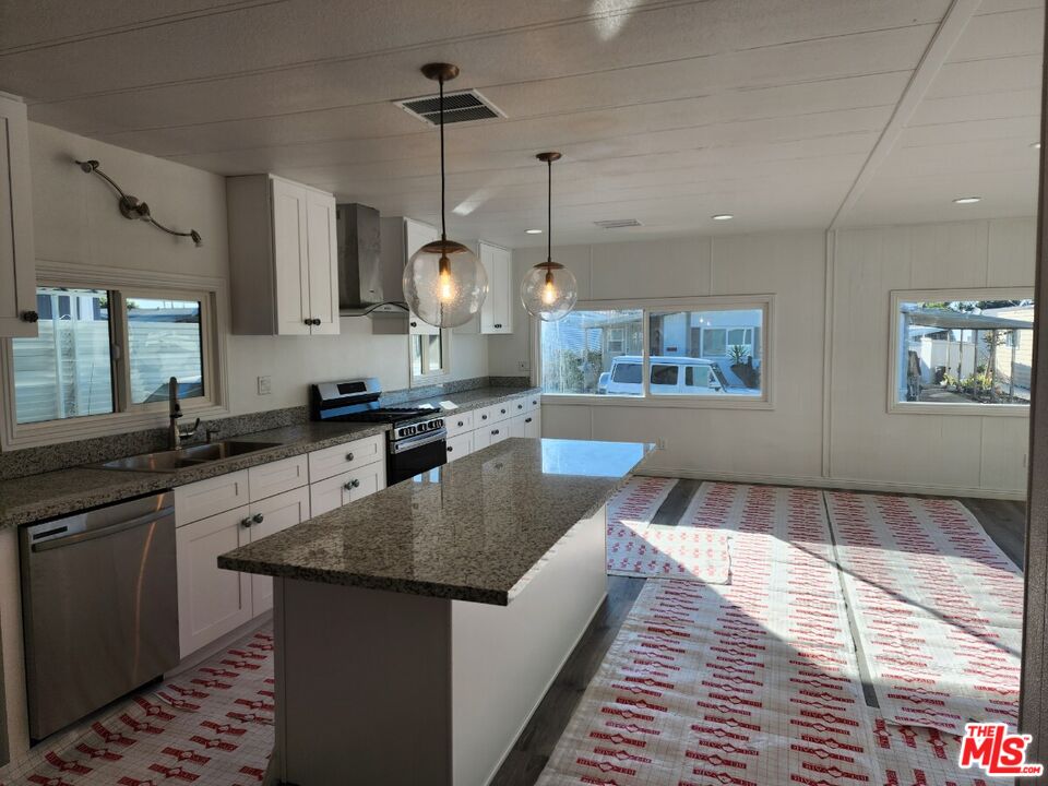 17700 South Avalon Boulevard, Unit 221 Carson, CA 90746 - Photo 2 of 14 a large kitchen with stainless steel appliances granite countertop a stove a sink dishwasher a refrigerator and white cabinets with wooden floor