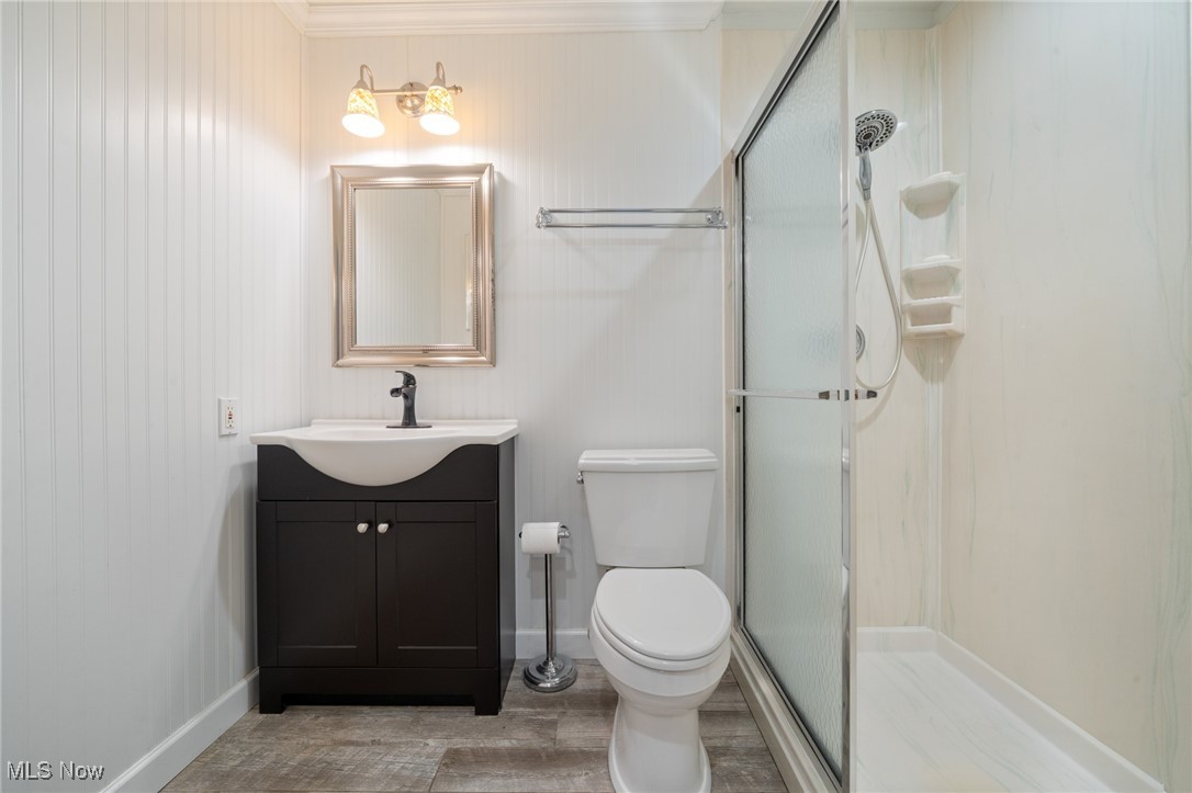 17800 Falling Leaves Road Strongsville, OH 44136 - Photo 22 of 39 Bathroom featuring vanity, toilet, baseboards, wood finished floors, and a stall shower