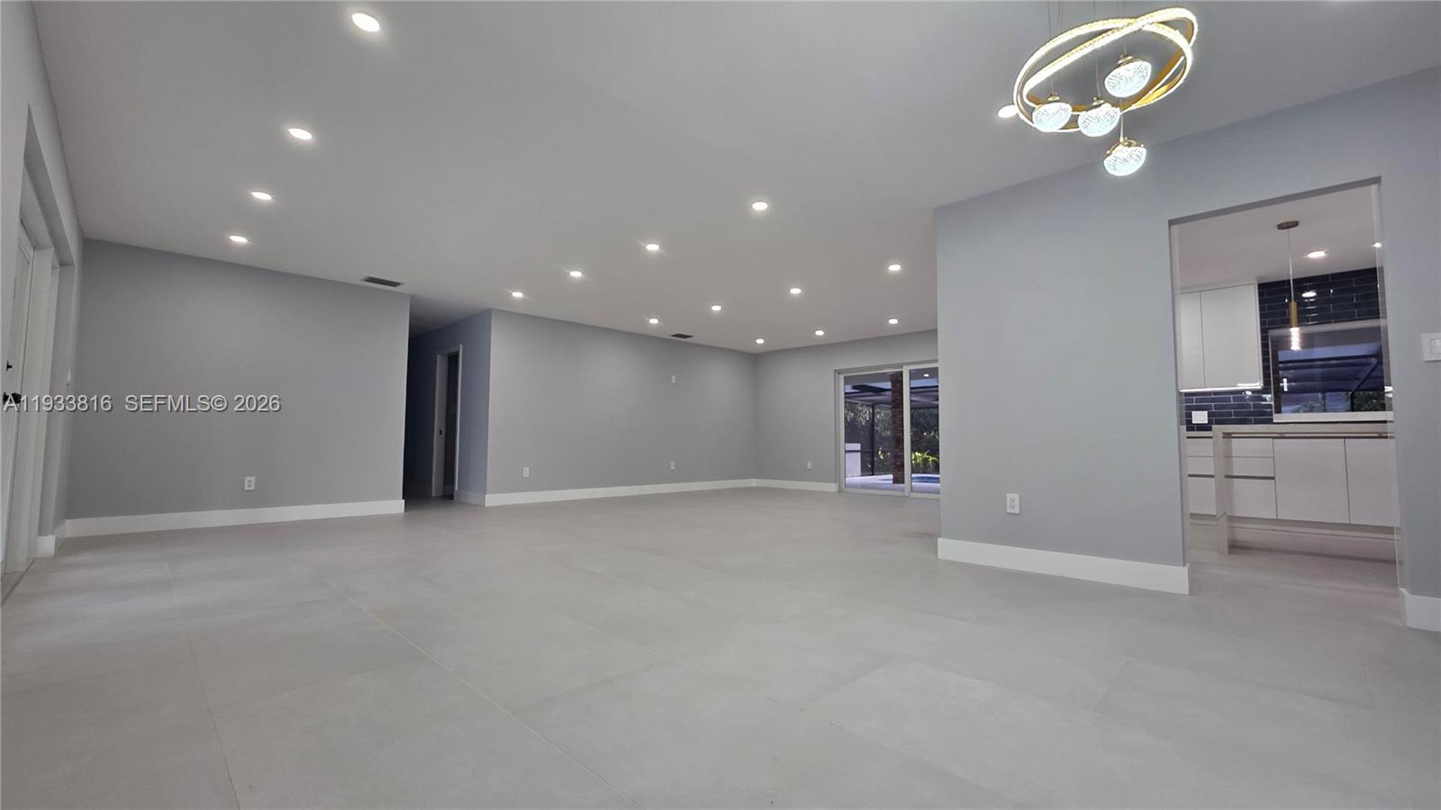 10540 Southwest 125th Street Miami, FL 33176 - Photo 5 of 31 an empty room with a kitchen and chandelier fan