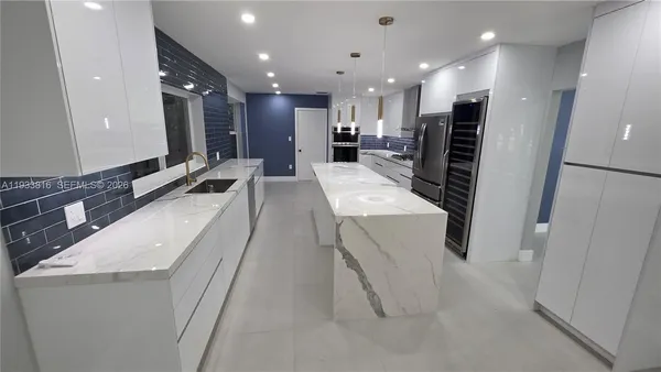 a large white kitchen with a large sink oven and stainless steel appliances