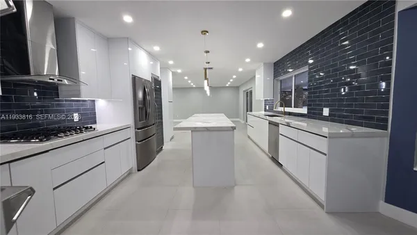 a large kitchen with stainless steel appliances kitchen island granite countertop a sink and cabinets