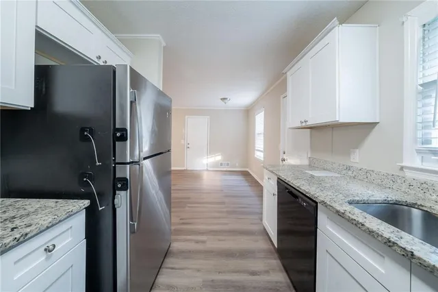a kitchen with stainless steel appliances granite countertop a refrigerator a sink and white cabinets