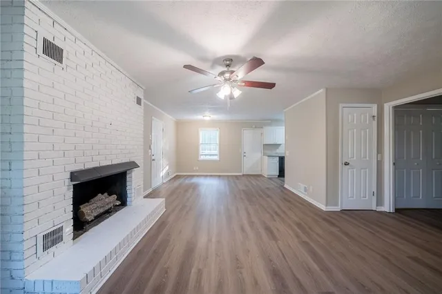 a view of an empty room with wooden floor fireplace and a window