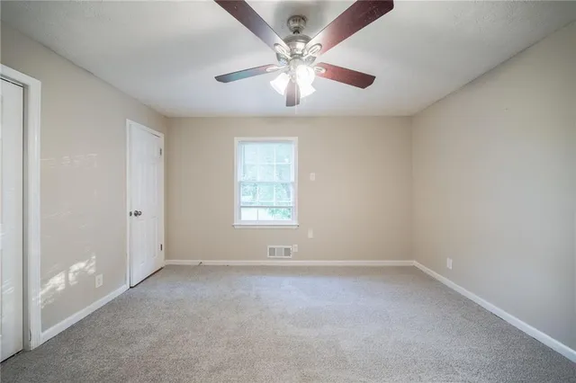 an empty room with a window and a fan
