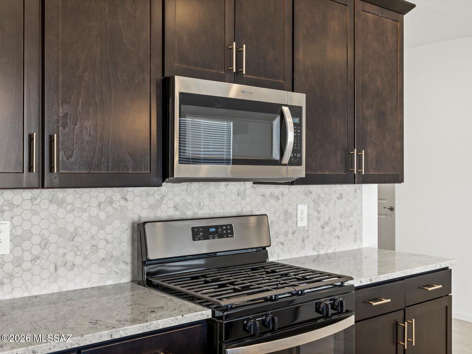 5133 West Gainer Ridge Road Tucson, AZ 85757 - Photo 14 of 16 a kitchen with granite countertop cabinets stove top oven and microwave