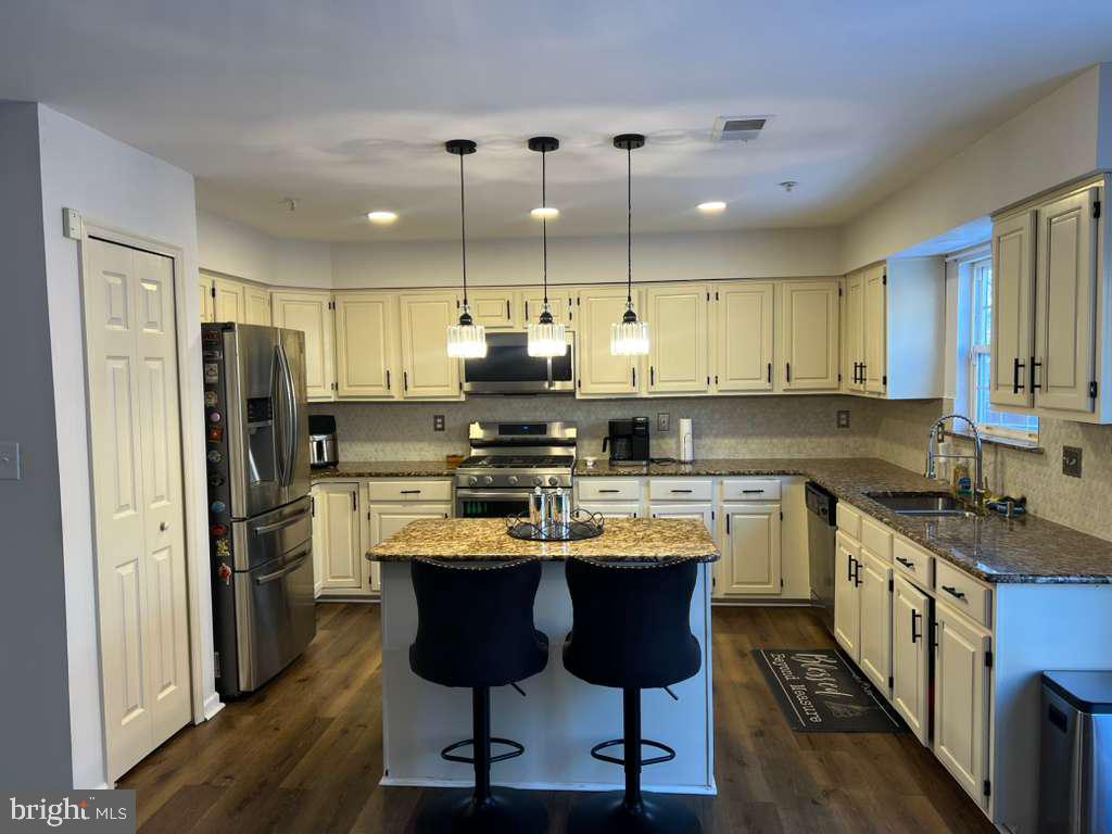 3650 Marcey Creek Road Laurel, MD 20724 - Photo 3 of 10 a kitchen with stainless steel appliances granite countertop a sink a stove a refrigerator and island with wooden floor