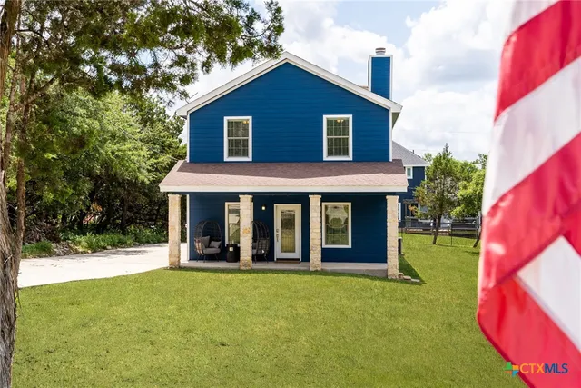 a view of a house with a yard and potted plants