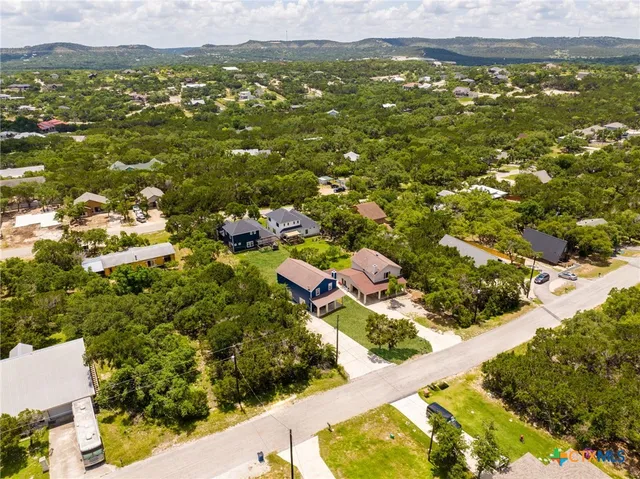 an aerial view of residential houses with outdoor space and trees
