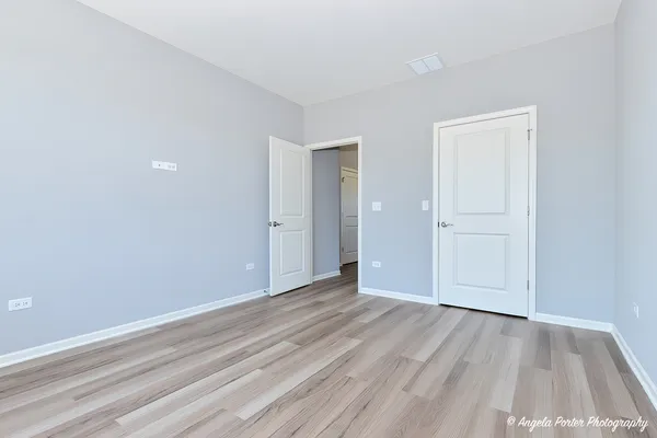 a view of an empty room with wooden floor and closet