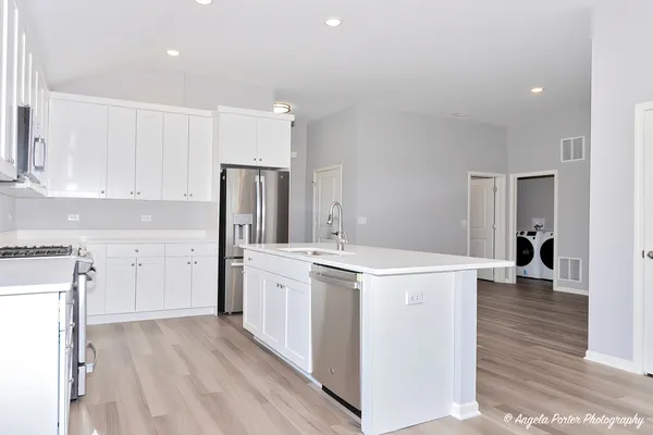a kitchen with a stove a refrigerator and a sink with wooden floor