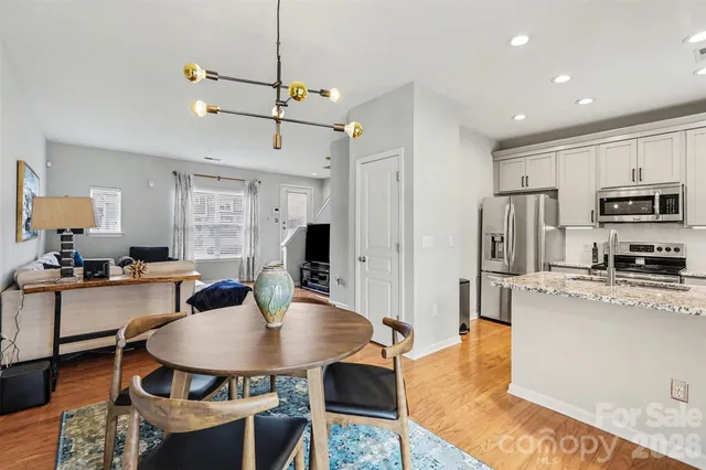 a kitchen with stainless steel appliances granite countertop a stove a refrigerator a kitchen island a dining table and chairs