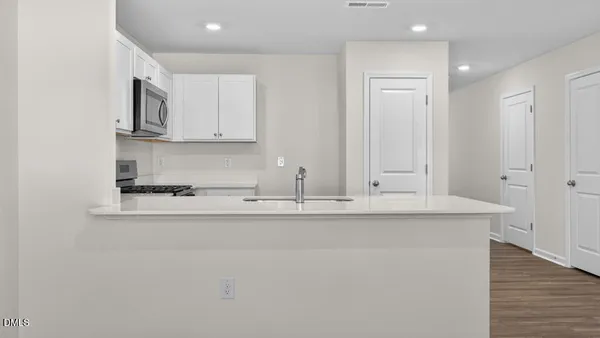 a view of kitchen with stainless steel appliances granite countertop white cabinets and a refrigerator