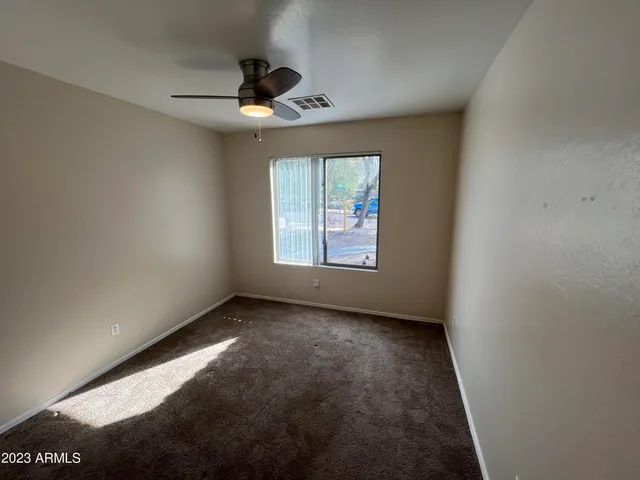 en empty room with windows and ceiling fan