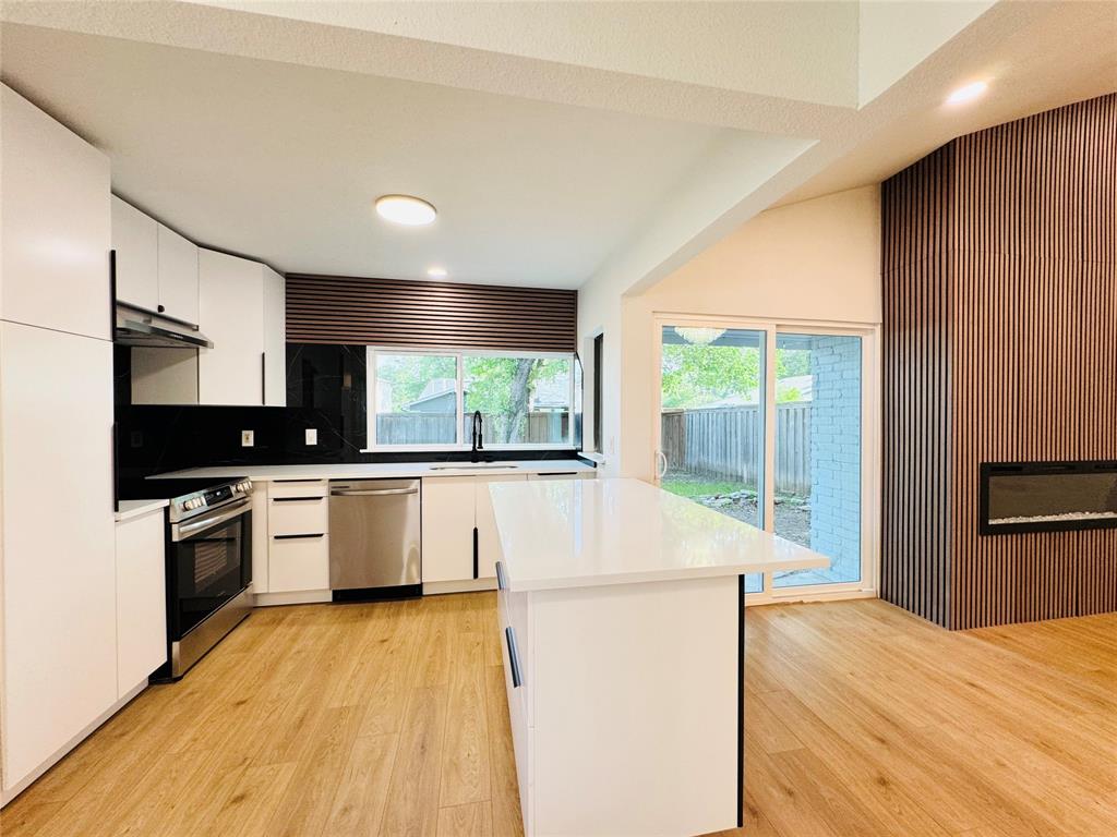 a kitchen with kitchen island granite countertop wooden floors and stainless steel appliances