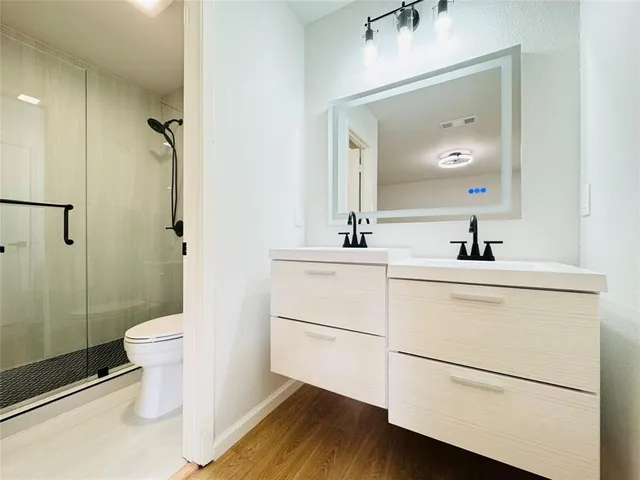 a bathroom with a sink a toilet a mirror and shower