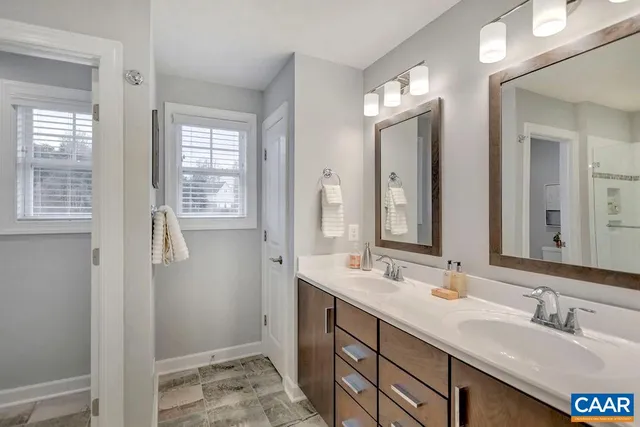 a bathroom with double vanity sink a mirror and a shower