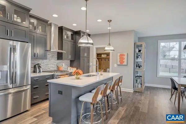 a kitchen with stainless steel appliances a dining table chairs refrigerator and sink