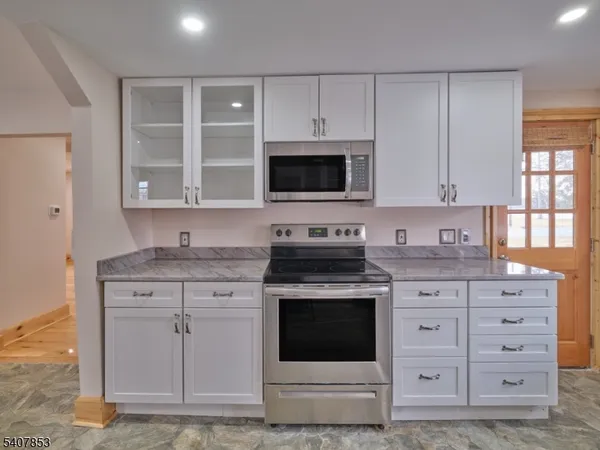 a kitchen with granite countertop white cabinets and stainless steel appliances