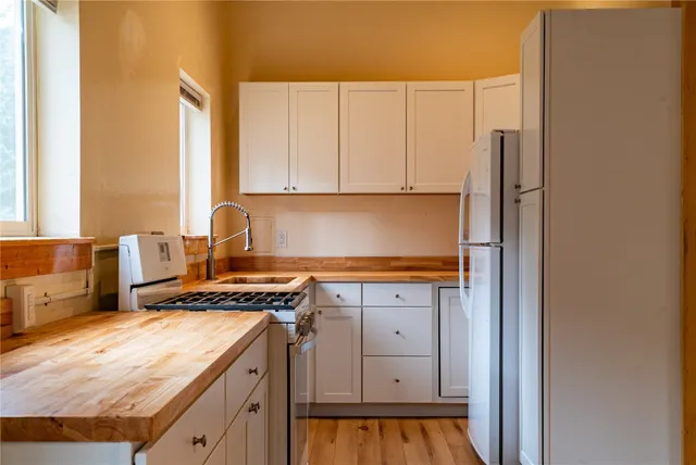 a kitchen with stainless steel appliances granite countertop a stove a sink and a refrigerator with cabinets