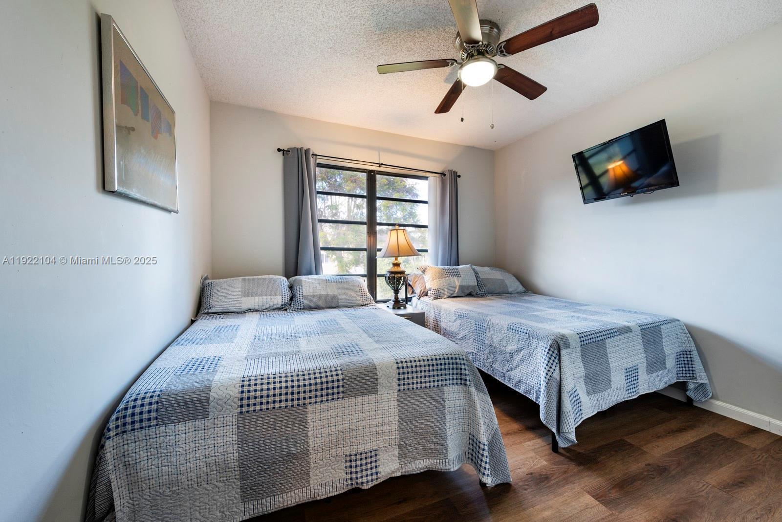 11724 Southwest 95th Street Miami, FL 33186 - Photo 19 of 25 a spacious bedroom with a bed and a flat screen tv