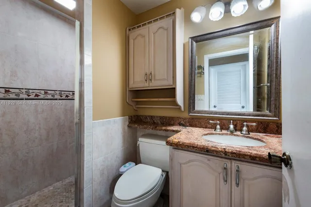 a bathroom with a granite countertop sink toilet and shower