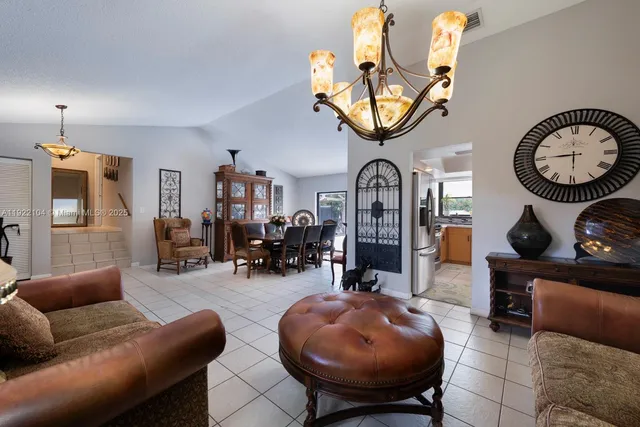 a living room with furniture a chandelier and a large mirror next to a window