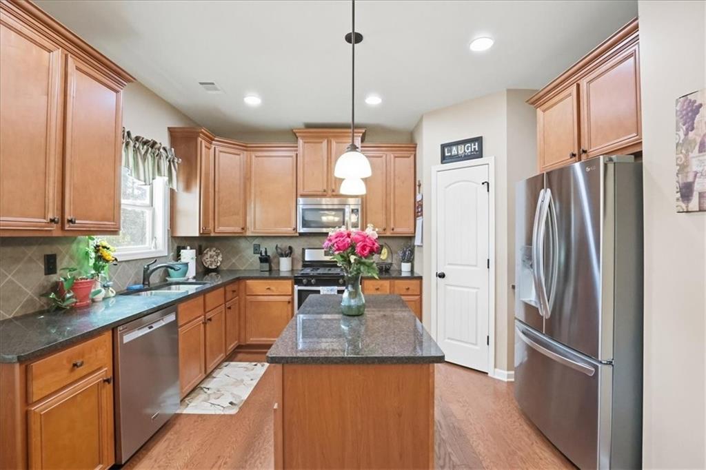 525 Widgeon Way Jefferson, GA 30549 - Photo 21 of 65 a kitchen with stainless steel appliances granite countertop a refrigerator a sink dishwasher a kitchen island with wooden cabinets and floor