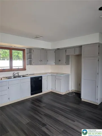 a kitchen with wooden floors and white cabinets