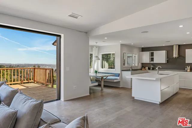 a living room with couches and kitchen view with wooden floor