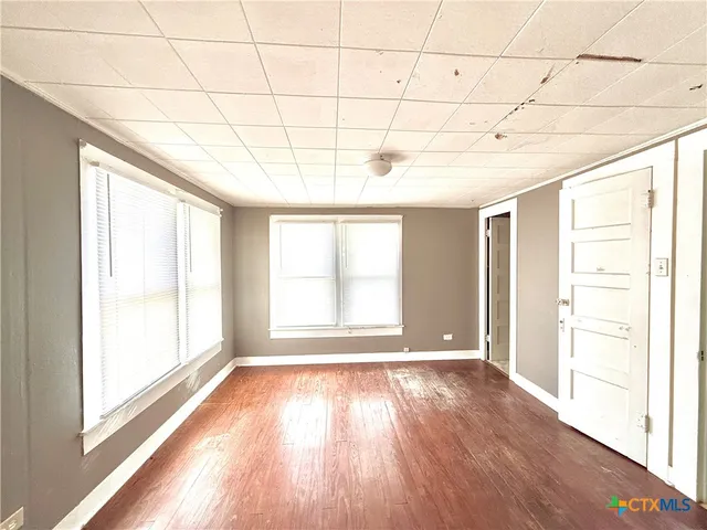 a view of an empty room with a window and wooden floor