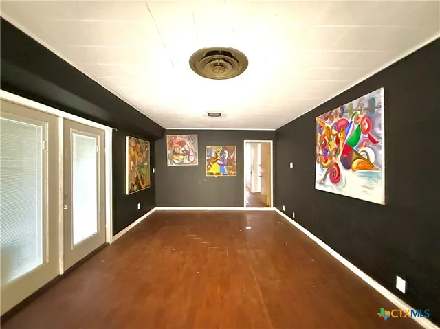 a view of an empty room with window and kitchen