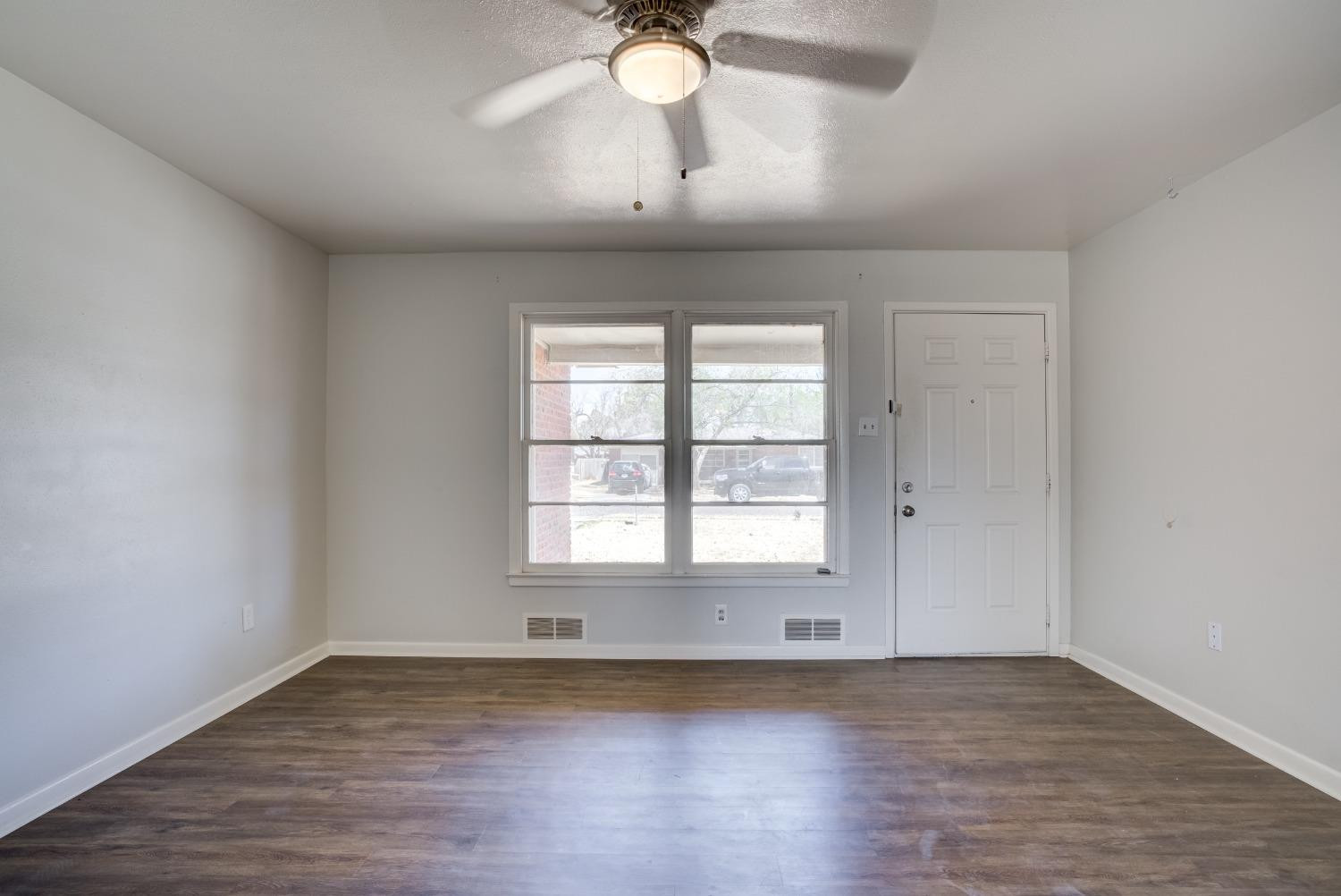 3011 44th Street Lubbock, TX 79413 - Photo 3 of 19 an empty room with wooden floor and windows