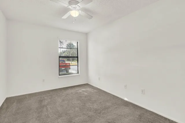 an empty room with windows and fan