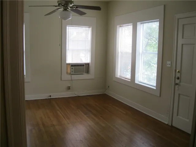 a view of an empty room with a window and wooden floor