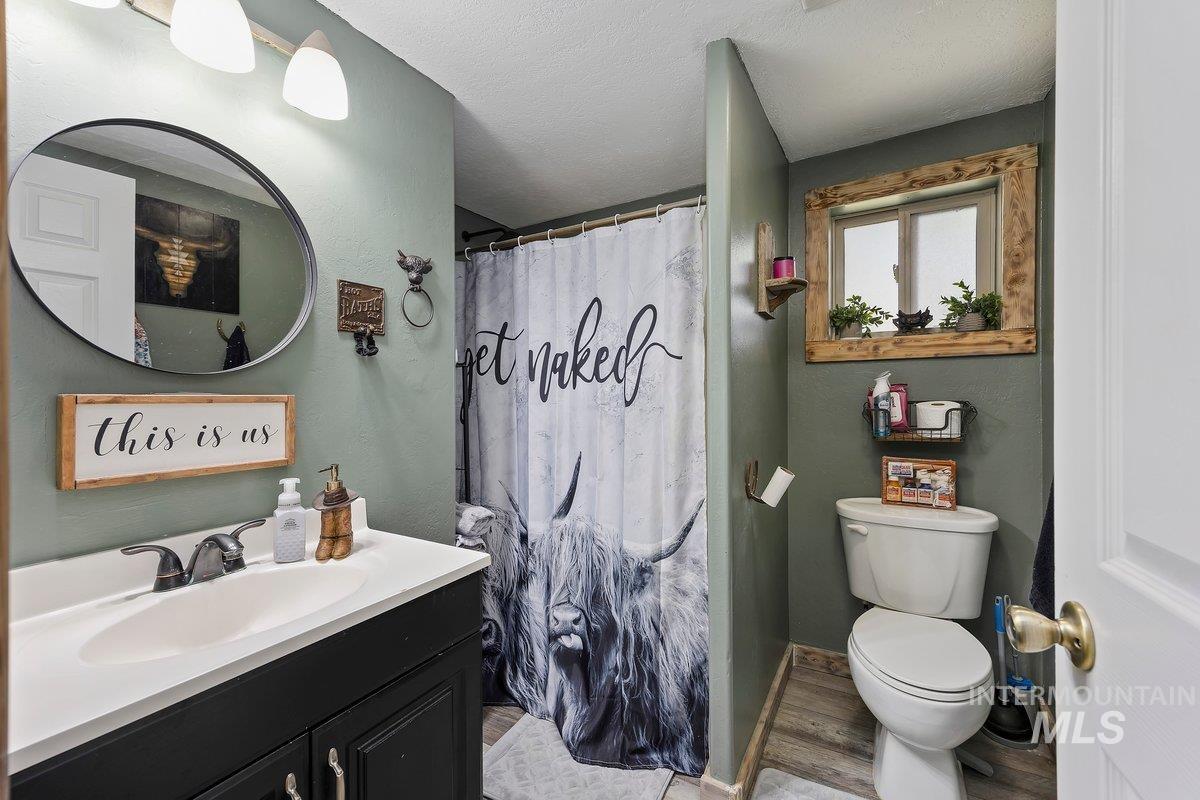 418 South Date Street Shoshone, ID 83352 - Photo 16 of 36 Bathroom featuring a black vanity with a white countertop, oval mirror, and overhead lighting